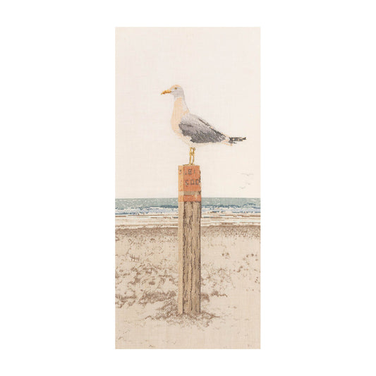 Seagull perched on a wooden post with a beach scene cross stitch