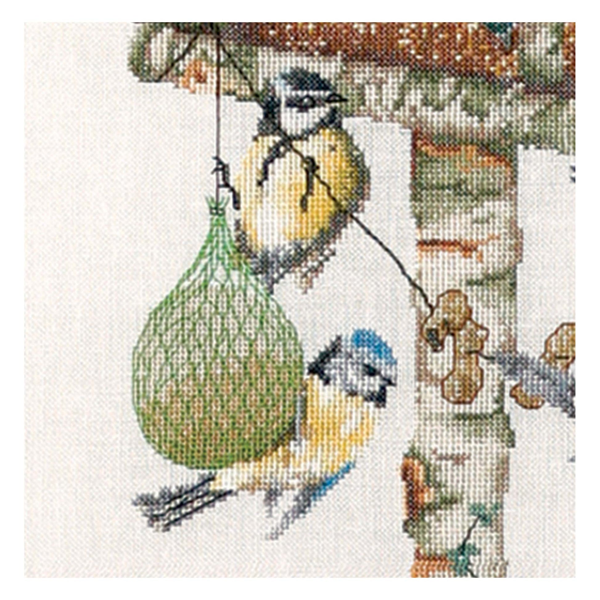 Cross-stitched design of birds near a birdhouse and bird feeder Thea gouverneur