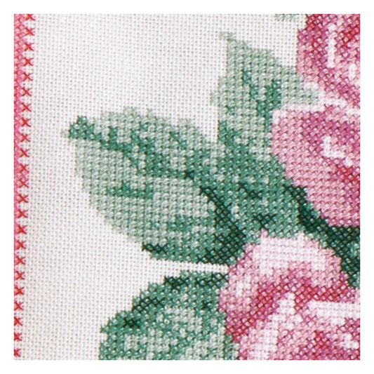 Close-up of a cross-stitched floral design with pink flowers and green leaves on white fabric.
