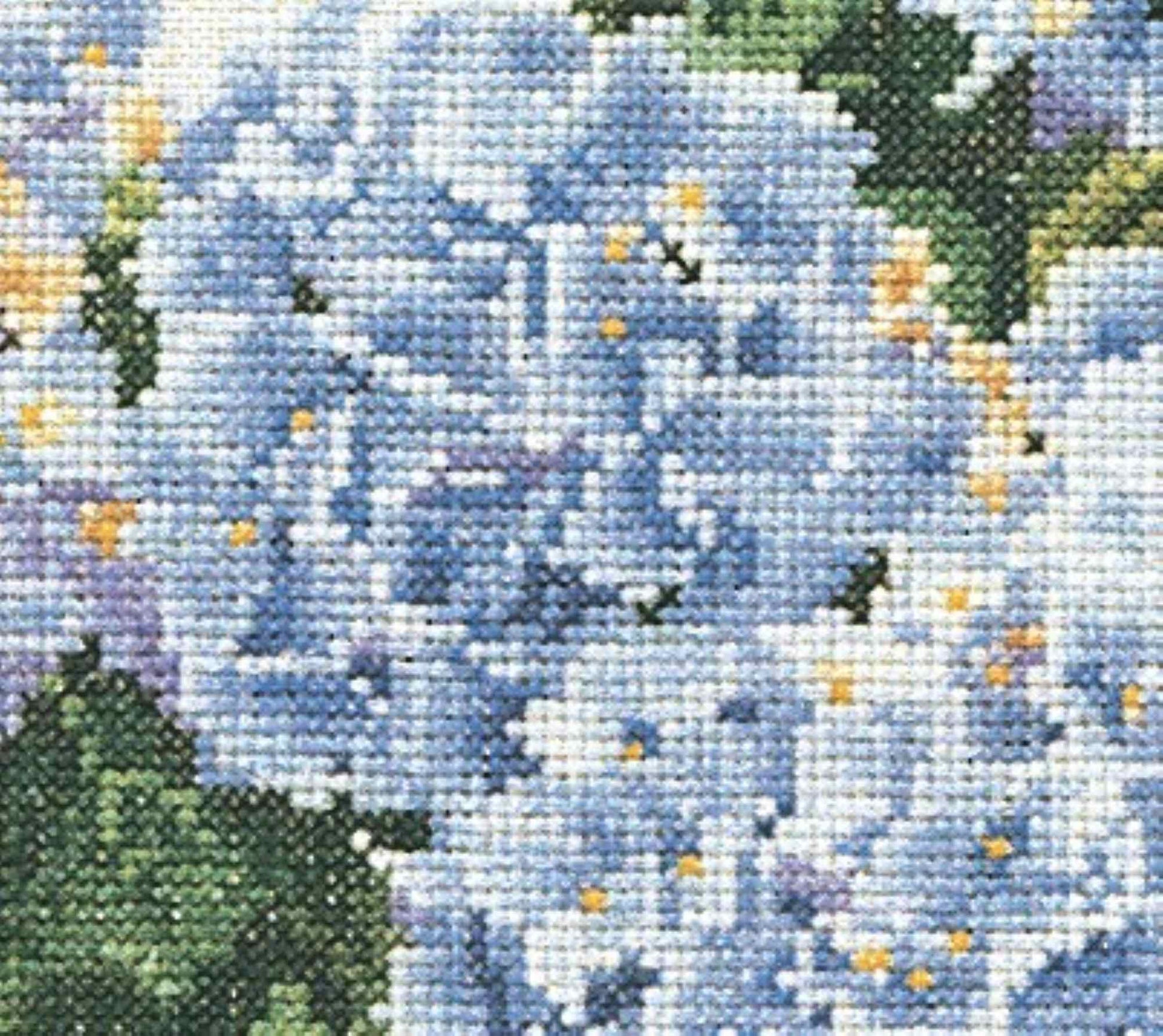 Close-up of a cross-stitched pattern with blue flowers and green leaves.
