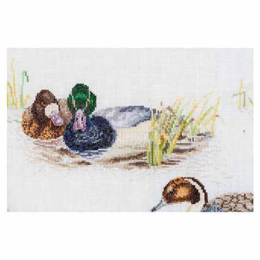Cross-stitched design of ducks in a pond with grass and reeds close up