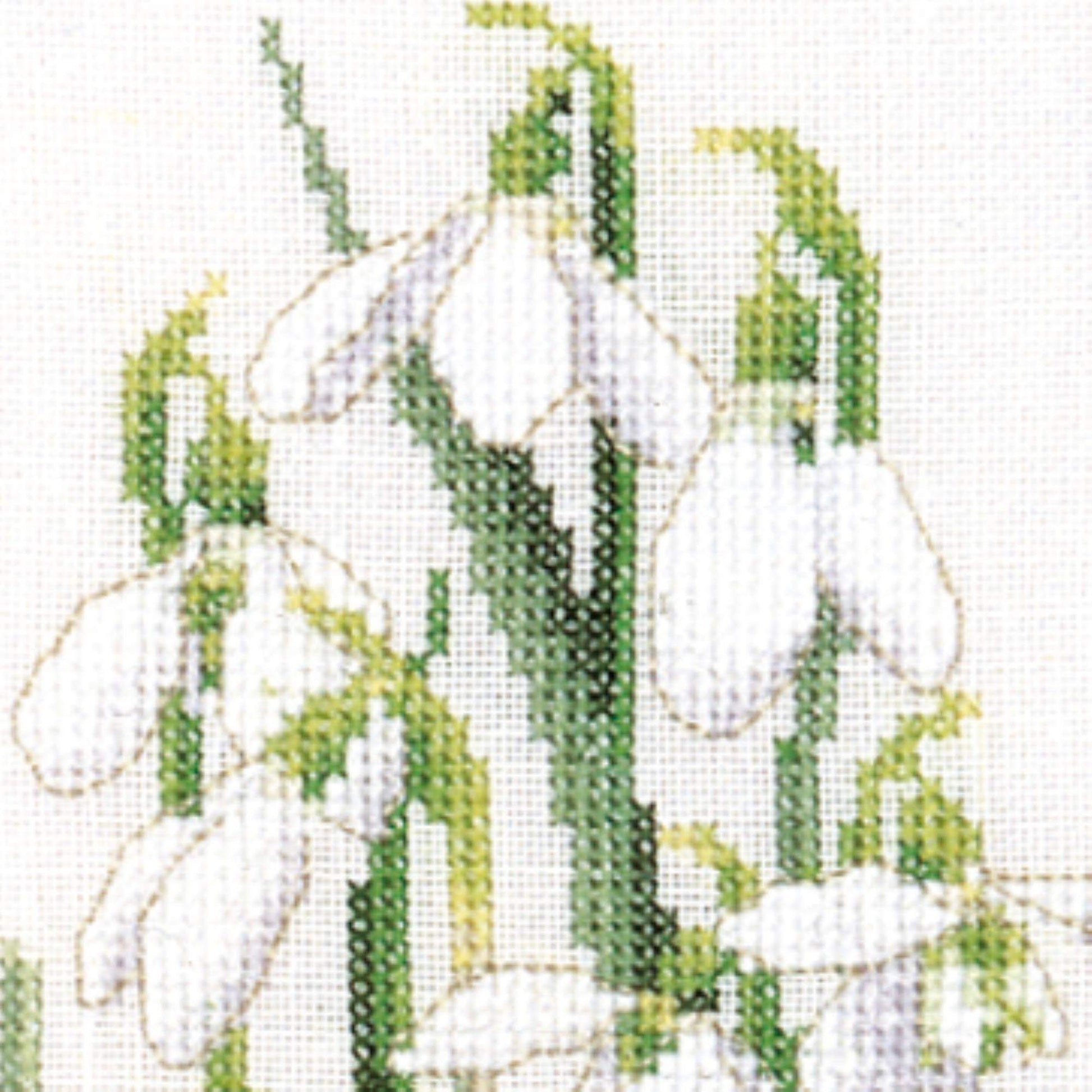 Cross-stitched design of a white flowers with green leaves