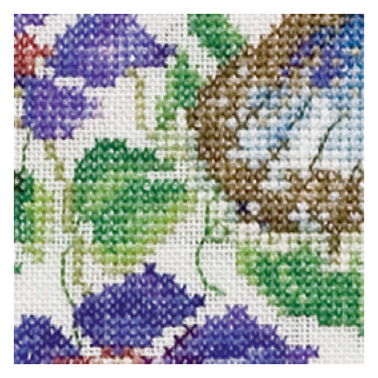 Close-up of a cross-stitched pattern with blue and green floral design on white fabric.