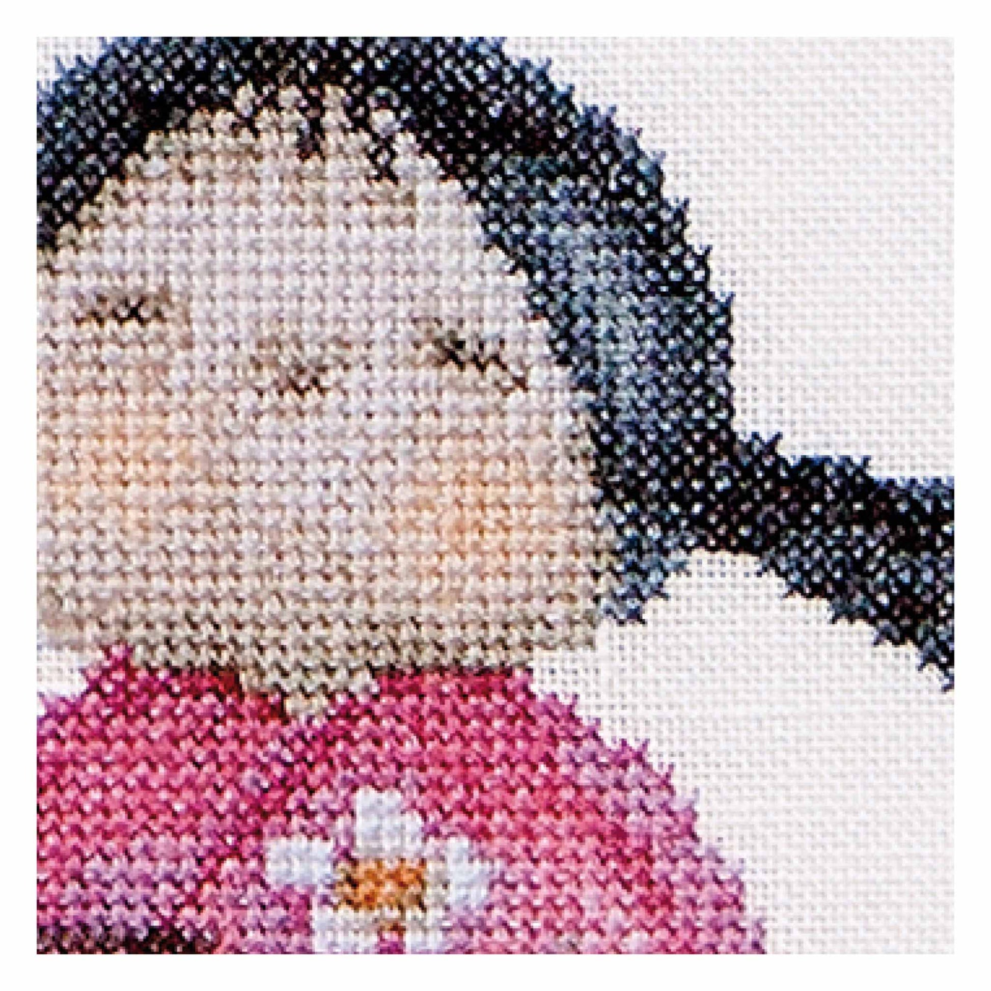 Cross-stitched portrait of a young girl with a pink dress and flower design Kokeshi close up