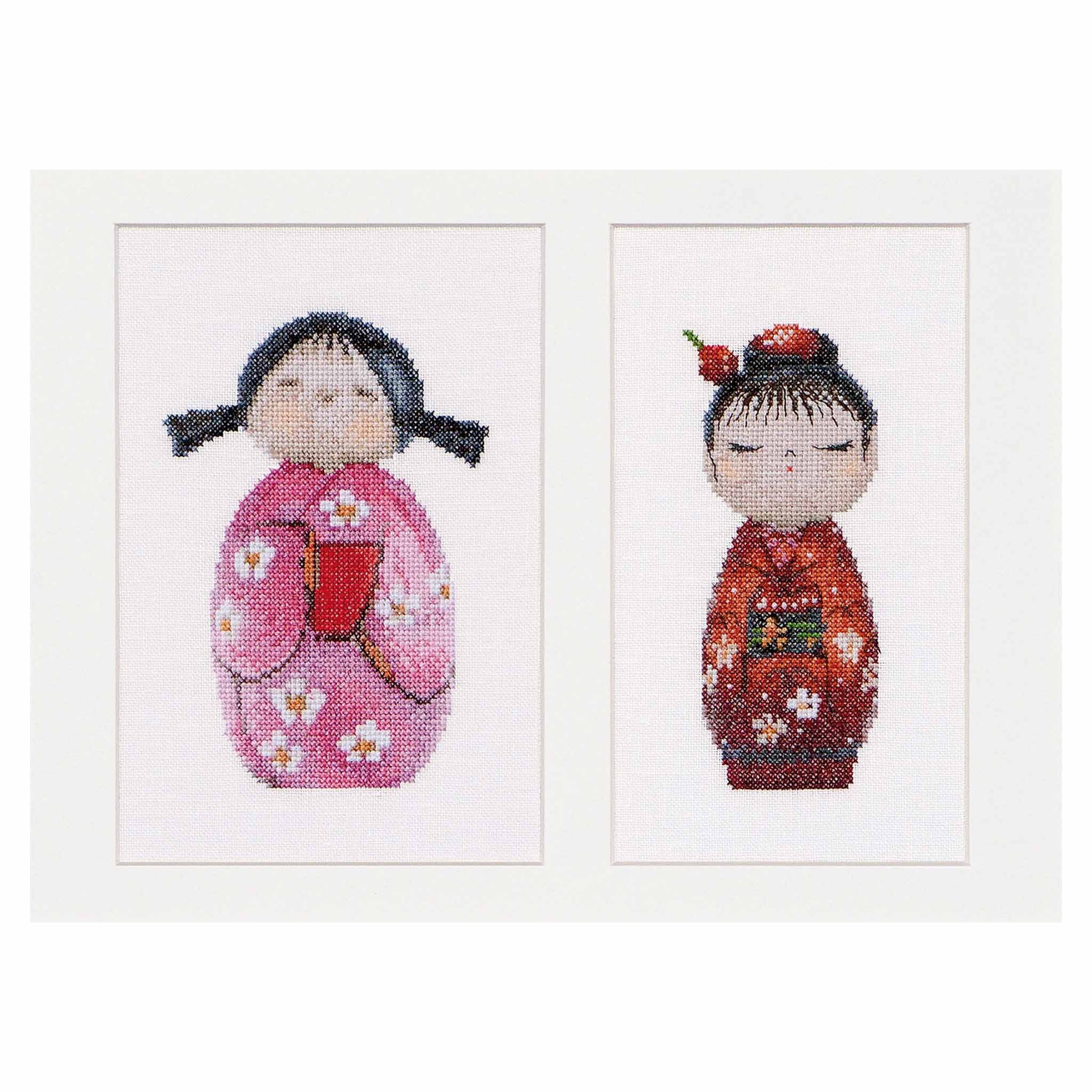 Two cross-stitched dolls in pink and red Kokeshi 