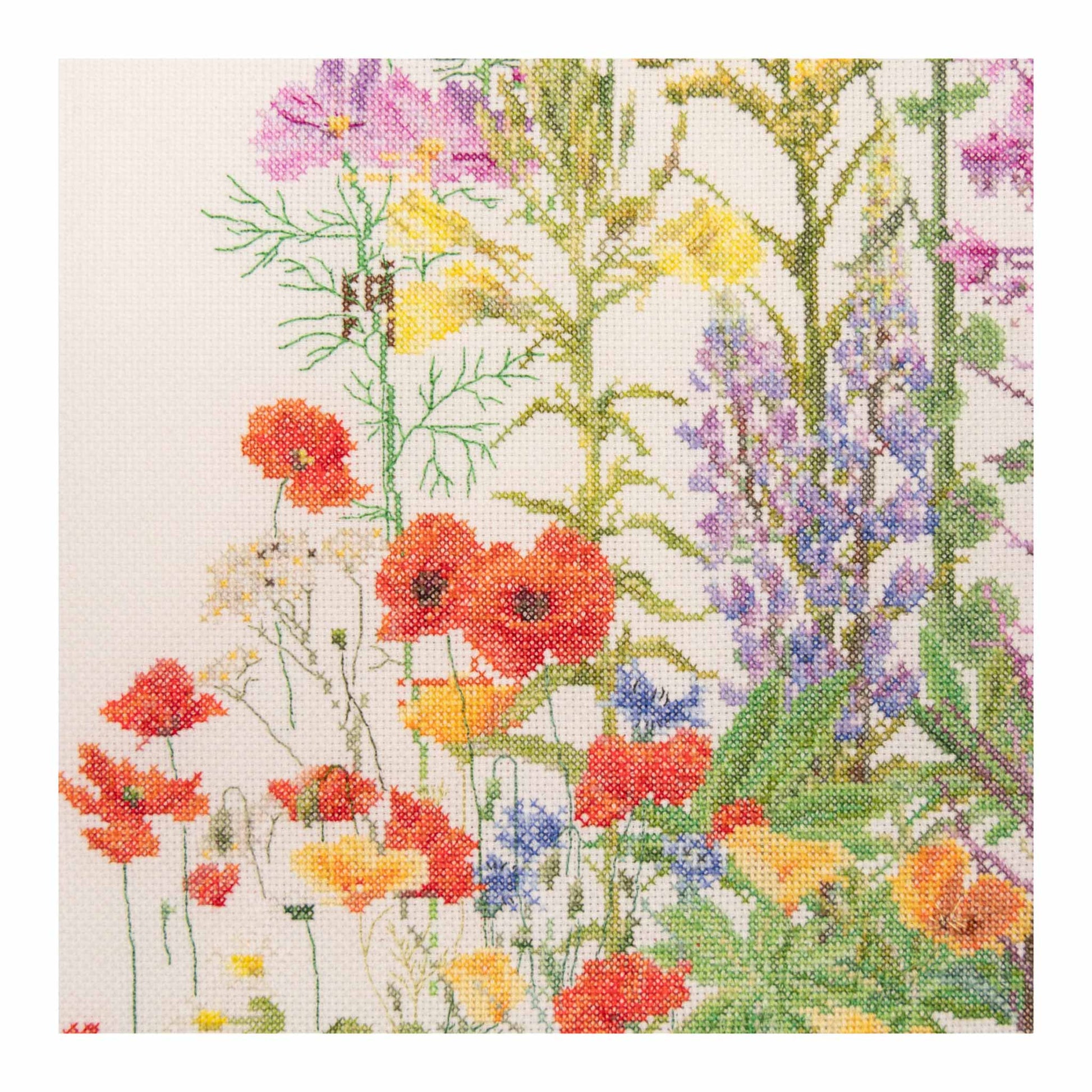 Close up cross stitch with a floral pattern of red, orange, yellow, and purple flowers on a white background.