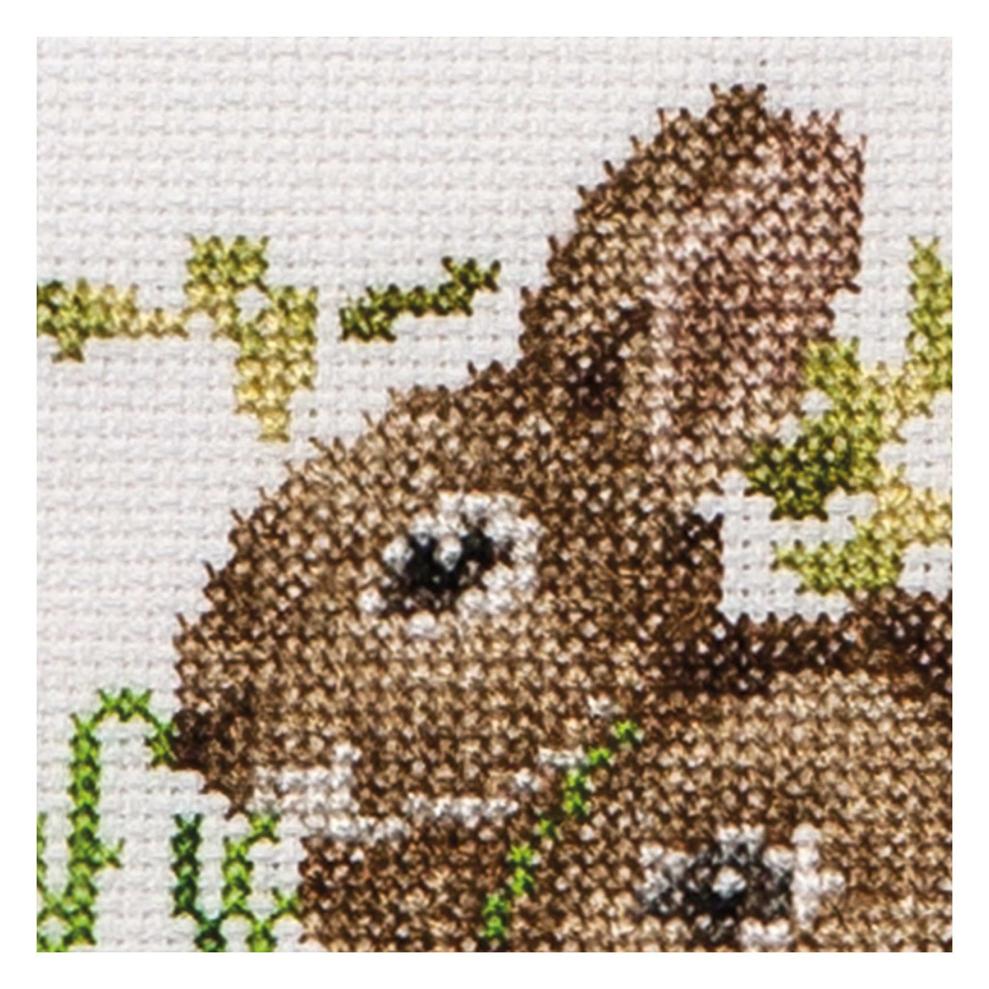 Cross-stitched bunny with green leaves close up