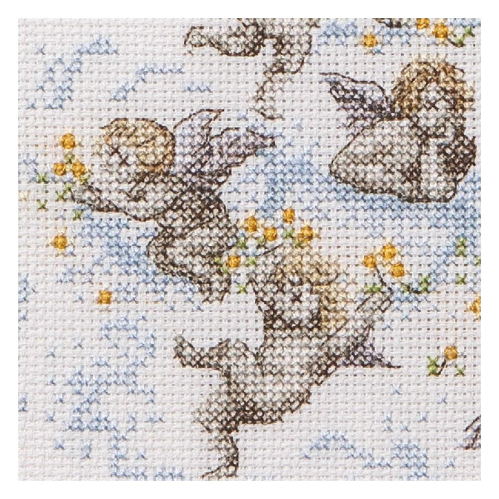 Cross stitch design of cherubs with flowers on a light blue clouds