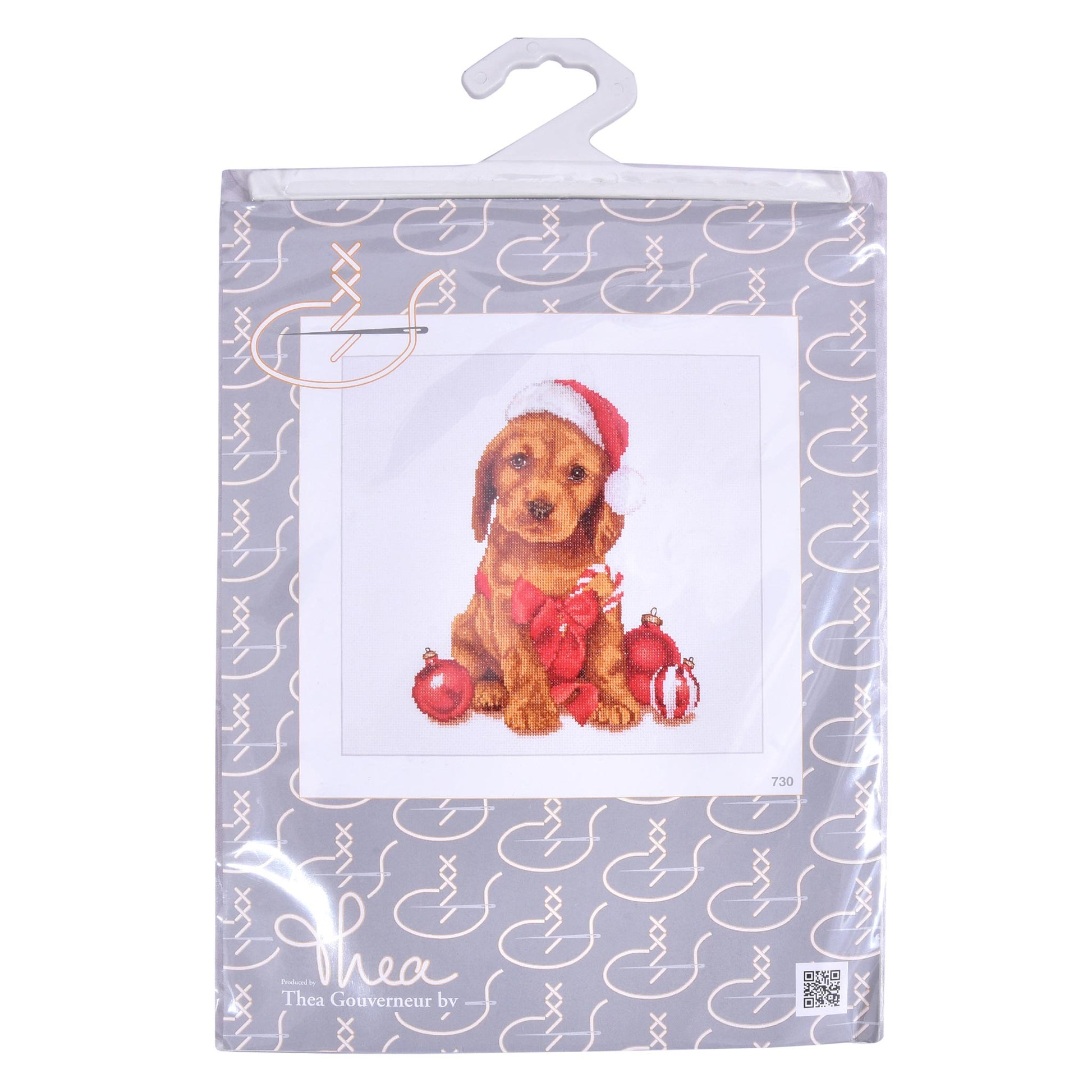 Packaged cross stitch kit with a Christmas-themed card featuring a dog in a Santa hat and red bow.