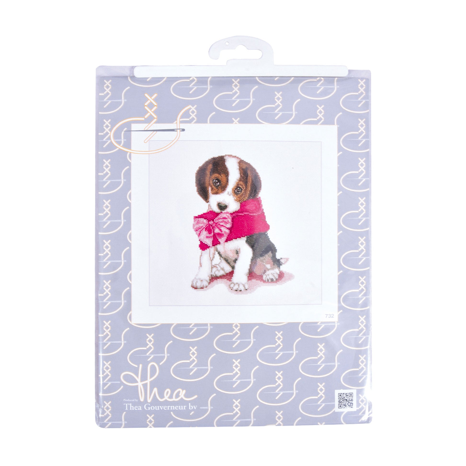Cross stitch packaging with a dog illustration and decorative elements on a light purple background