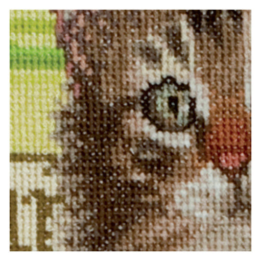 Close-up of a cross-stitched cat with a textured fabric background