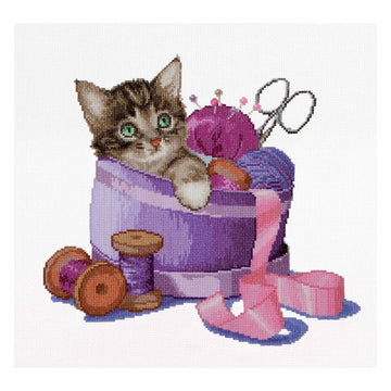 Cross-stitched design of a kitten in a purple basket with yarn and knitting tools on a white background