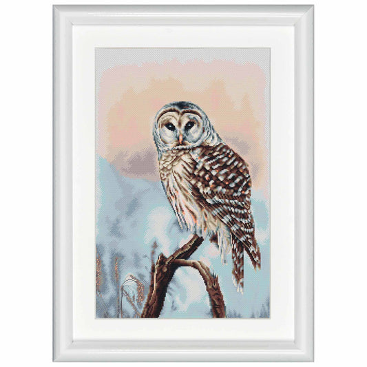 Cross-stitched owl on a branch with a snowy landscape in a white frame