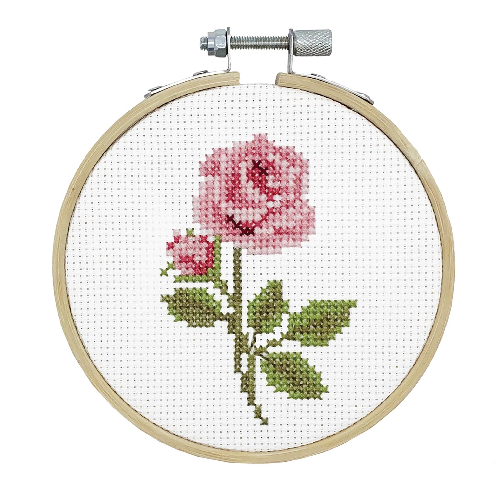 Cross-stitched pink rose in a wooden hoop on a white background