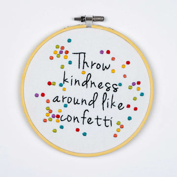 Embroidery on a hoop with colorful text on a white background