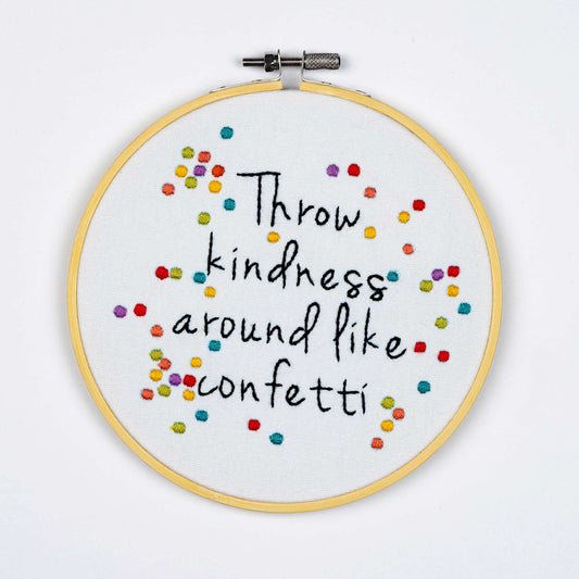 Embroidery on a hoop with colorful text on a white background