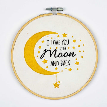 Embroidery on a hoop with 'I love you to the moon and back' text and yellow crescent moon design on a white background