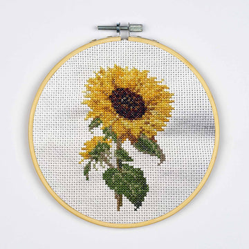 Cross-stitched sunflower in a wooden hoop on a white background