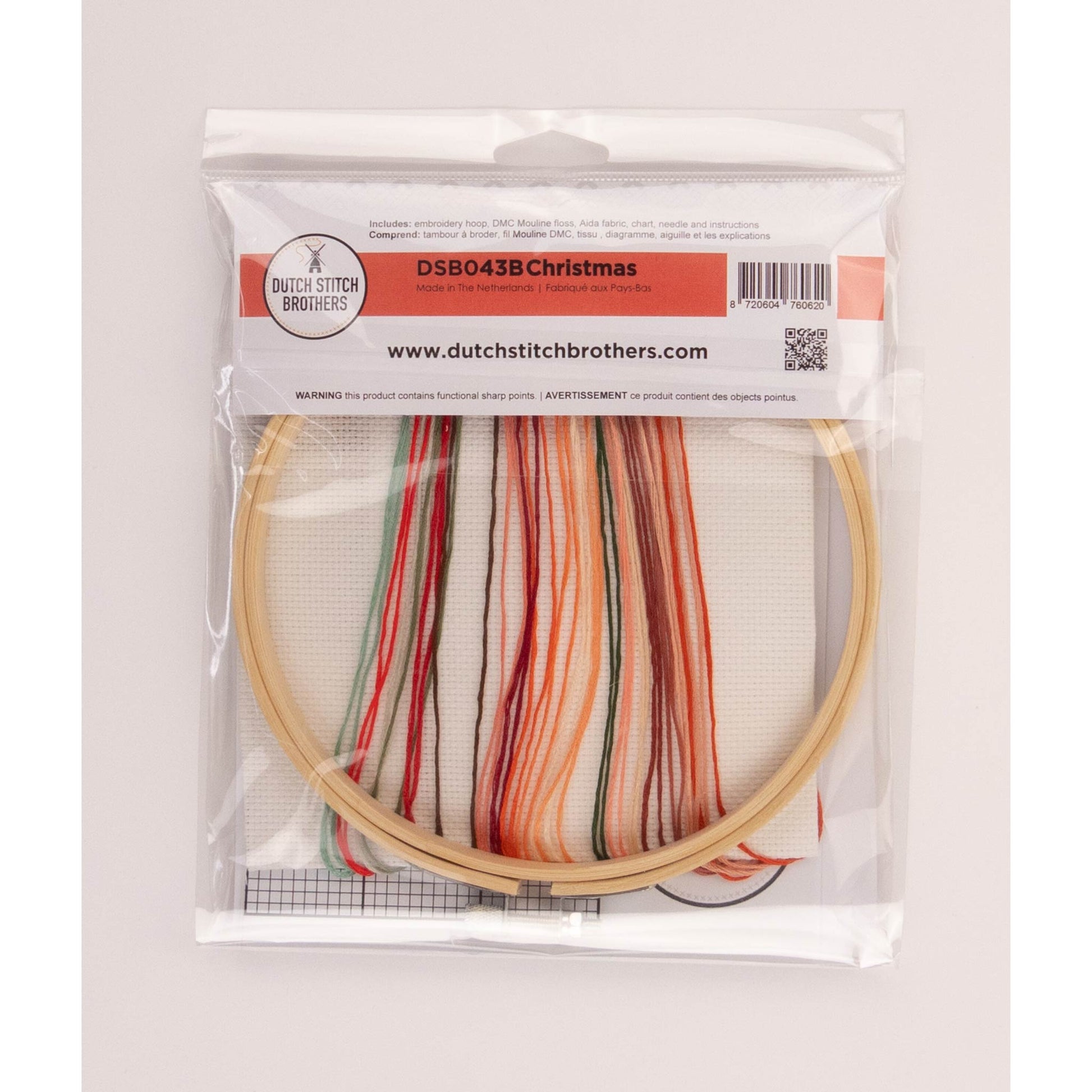 Cross stitch package including embroidery hoop, colorful floss, Aida fabric inside a clear package on a white background