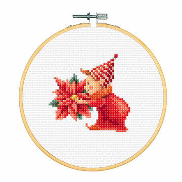 Cross-stitched design of a elf with a Christmas flower in a wooden hoop on a white background