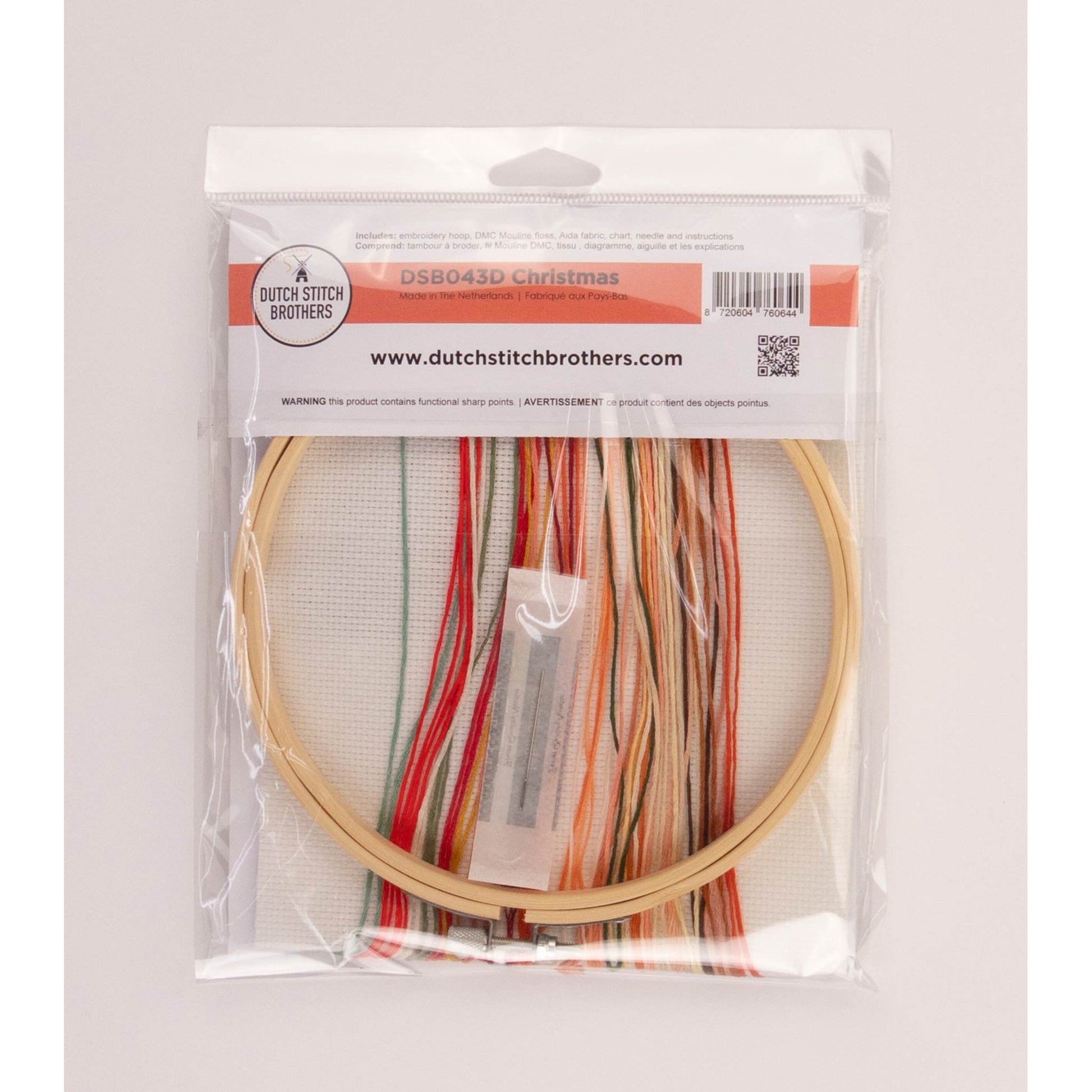 Cross stitch kit package including Embroidery hoop with colorful threads in a clear package on a light gray background