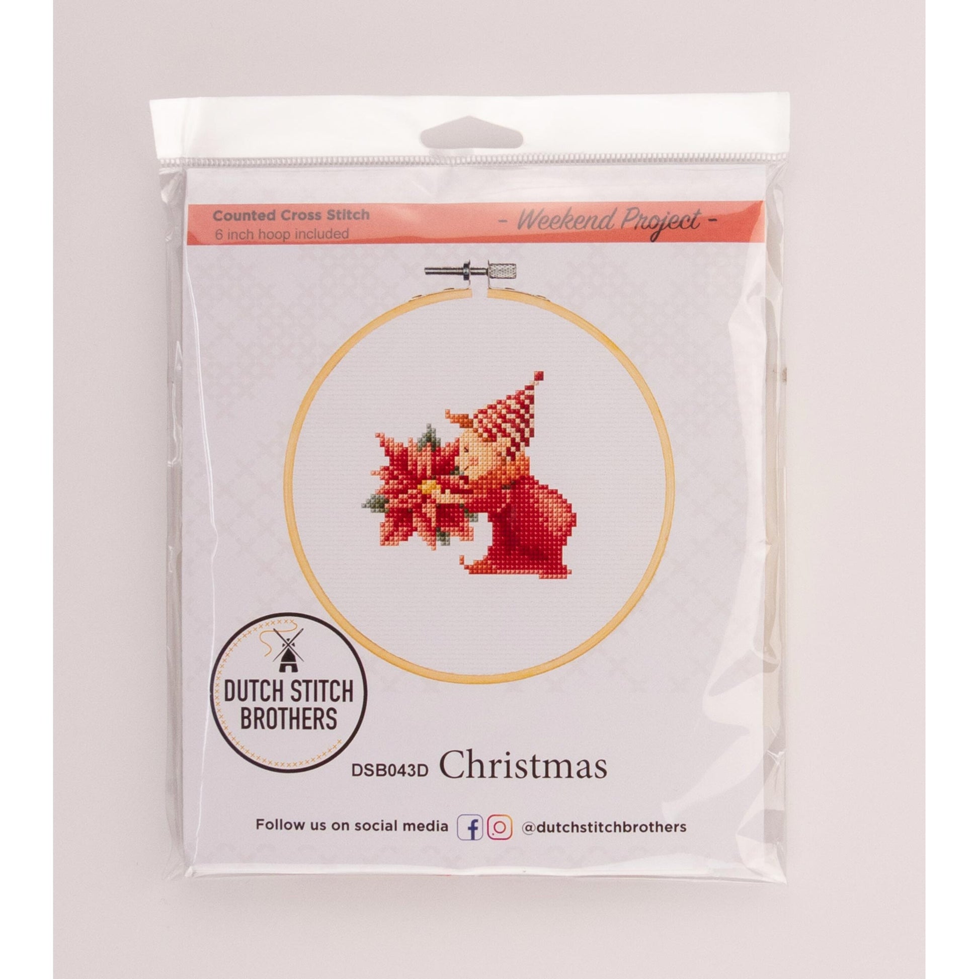 Cross-stitch kit with a Christmas-themed design of an elf and flower in a clear package Dutch Stitch Brothers brand.