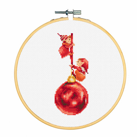 Cross-stitched design of two elves on a red Christmas ball in an embroidery hoop