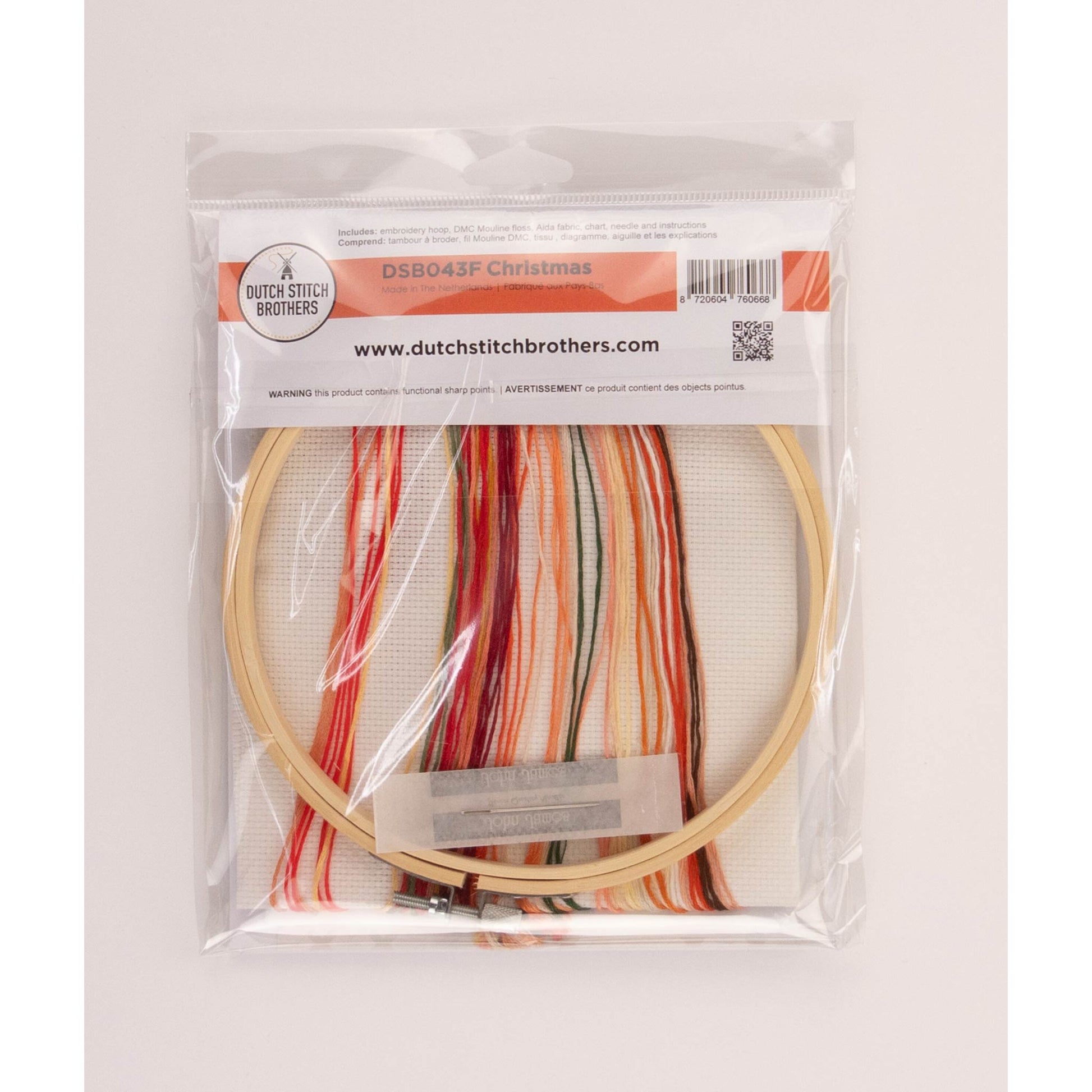 Cross stitch kit package with Embroidery hoop, colorful threads and Aida fabric inside a clear package on a white background
