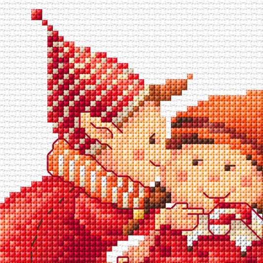 Cross-stitched design of a couple of elves wearing a red dress and hat on a white background
